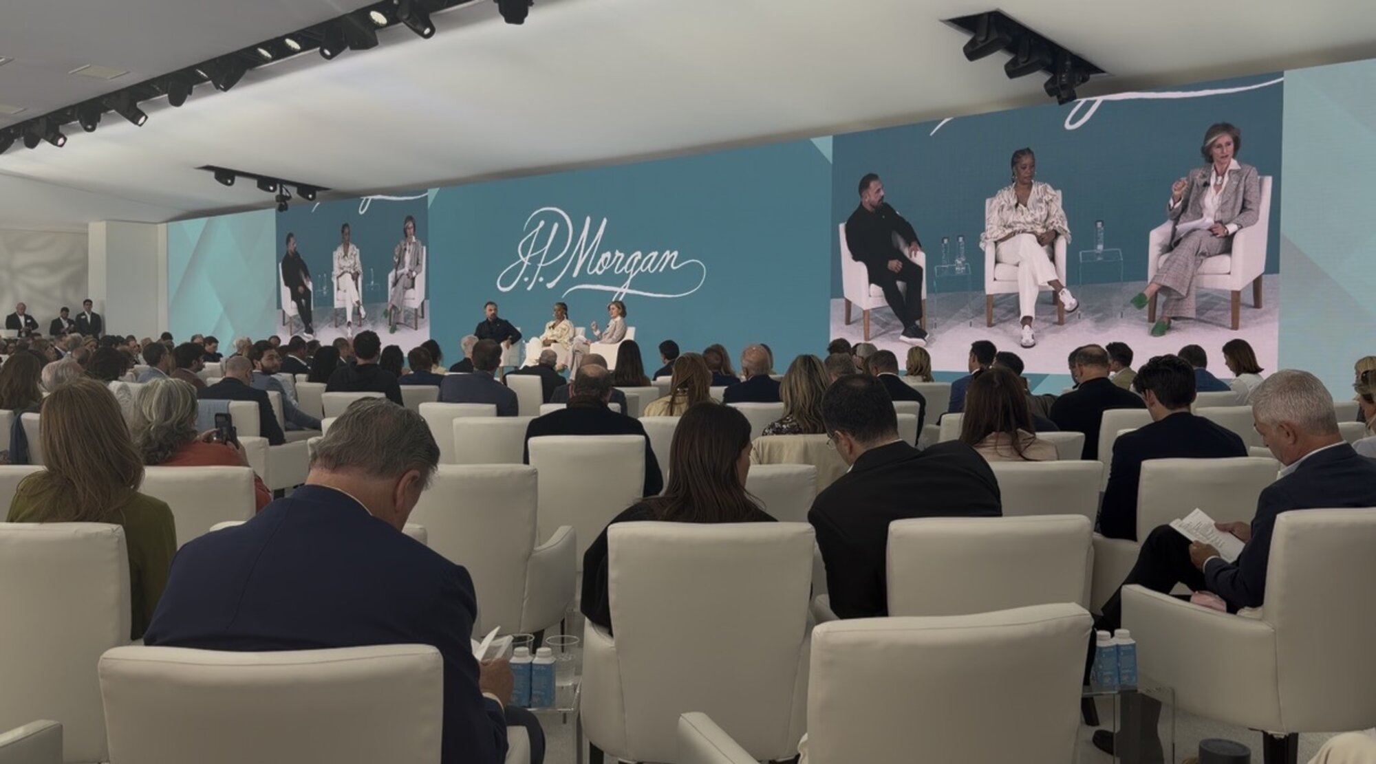 A full audience seated in front of a lit stage at a live event