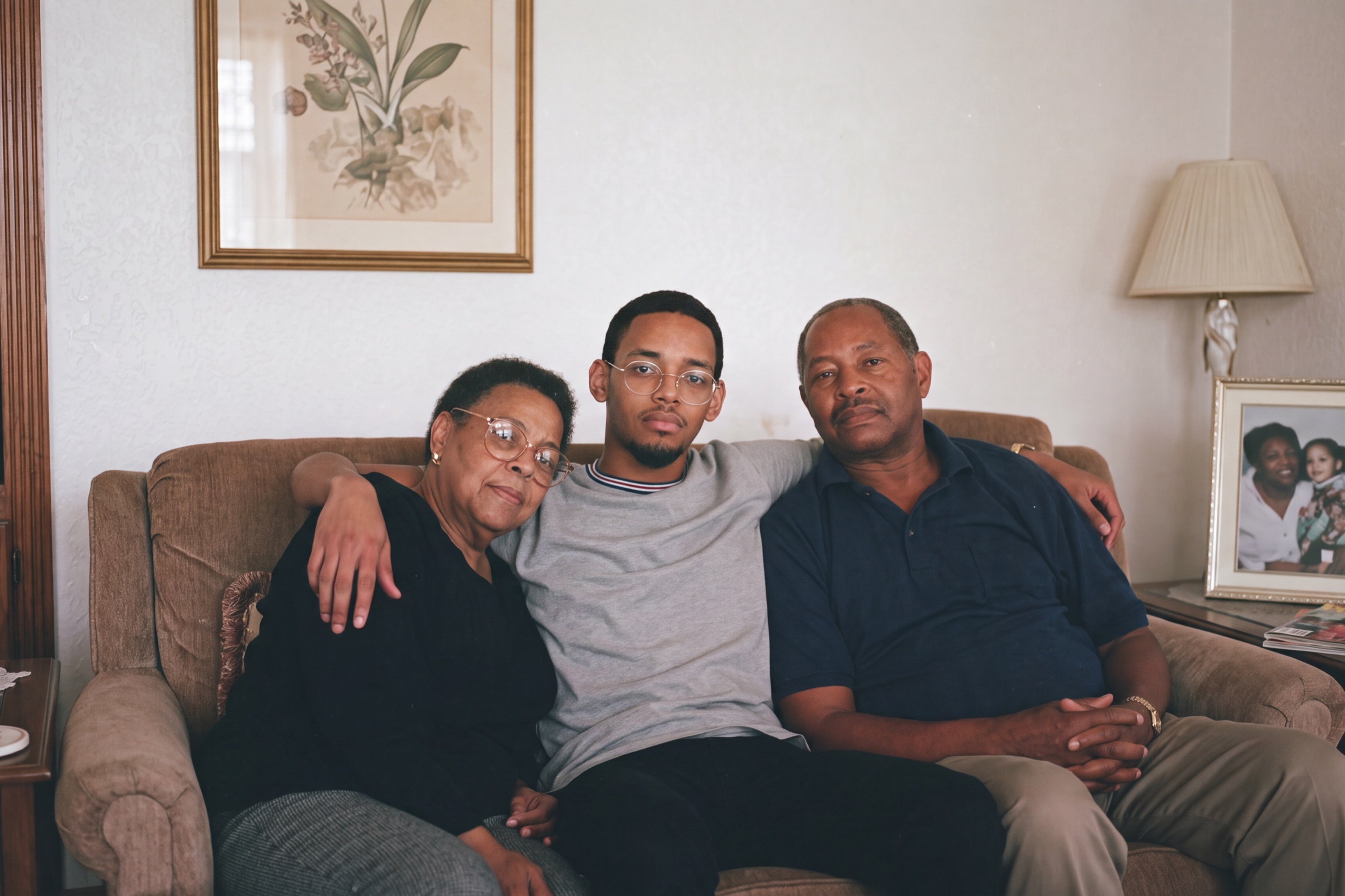 Three generations of a family posed together on a living-room sofa, facing the camera